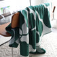 Leaf green and white knitted blanket draped over chair