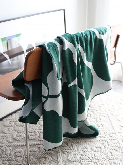 Leaf green and white knitted blanket draped over chair