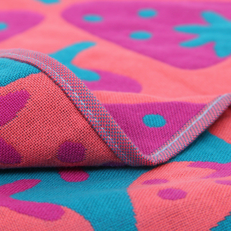 Close up of pink and teal cotton hand or face towel with strawberry pattern