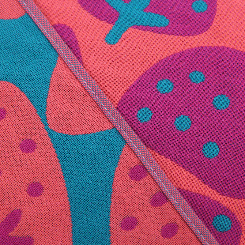 Close up of pink and teal cotton hand or face towel with strawberry pattern