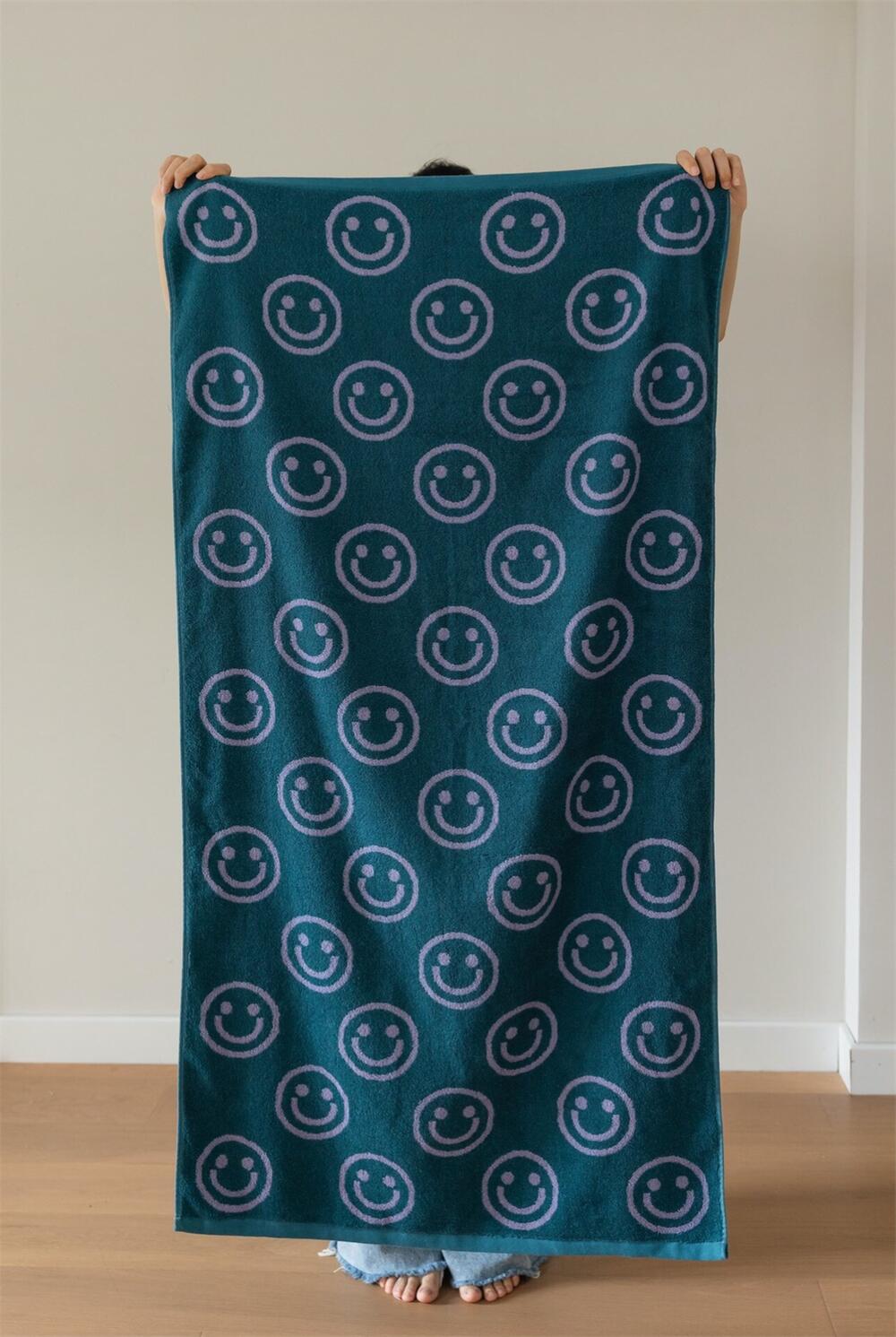 Green purple smiley face towel being held up