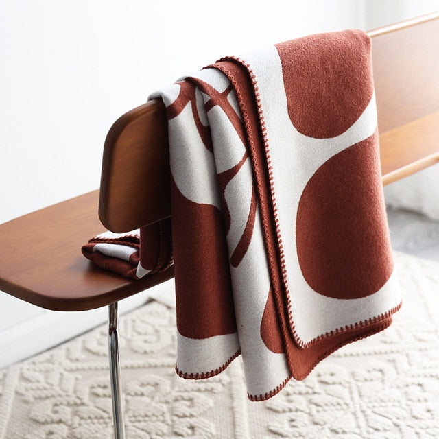 Rust red and white knitted blanket draped over chair