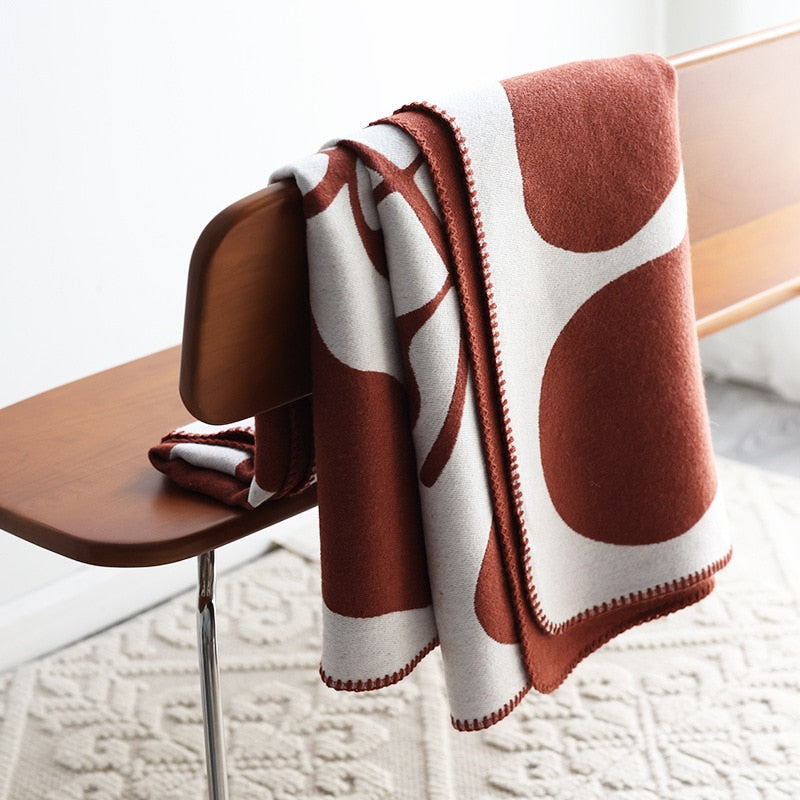 Rust red and white knitted blanket folded and draped over chair