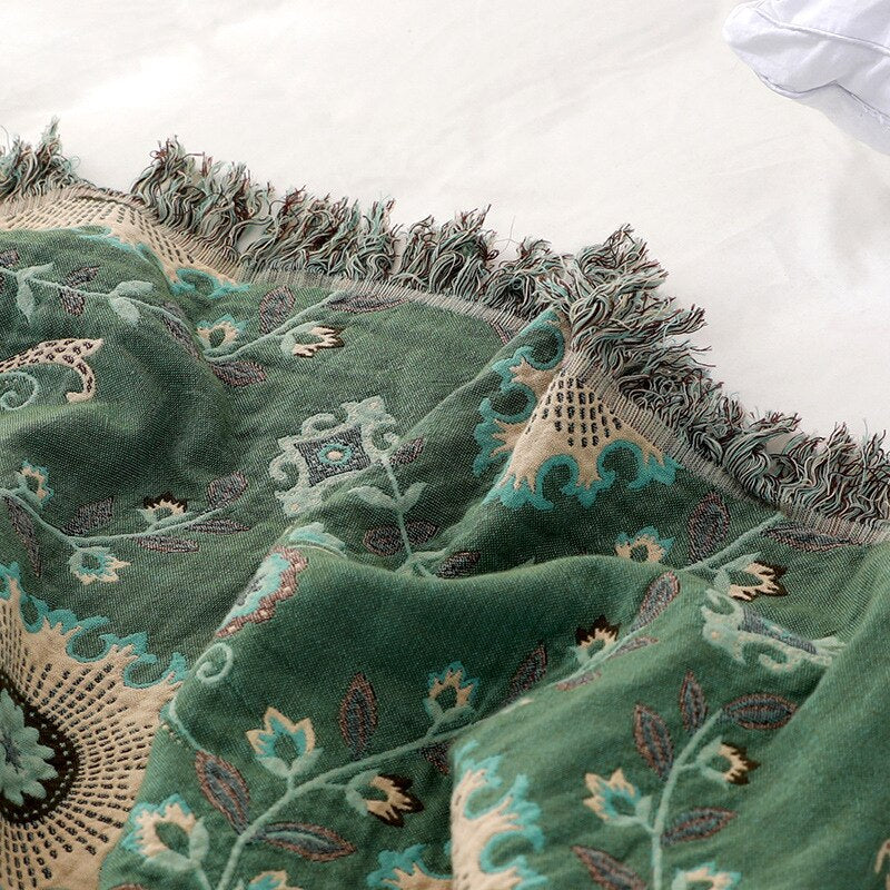 Close up of green and cream double sided fringed throw blanket with floral design