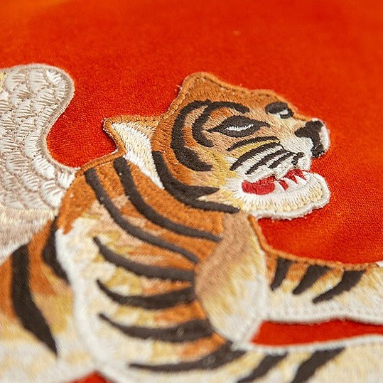 Close up of embroidered tiger on orange velvet cushion cover