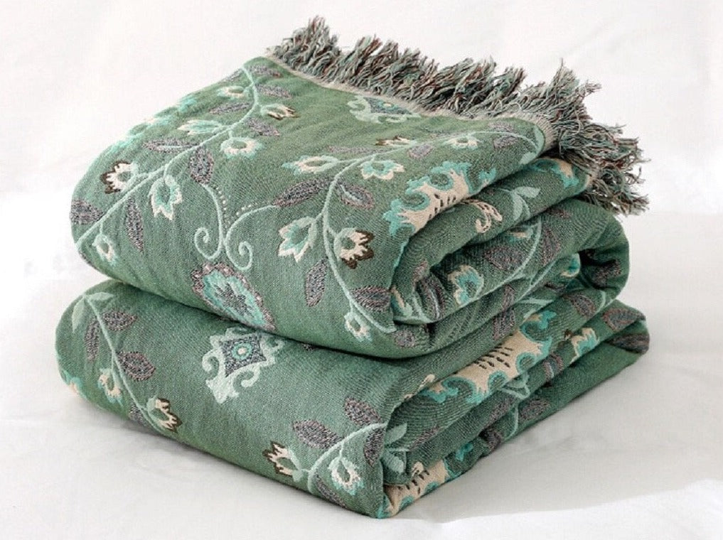 Folded green and cream double sided fringed throw blanket with floral design