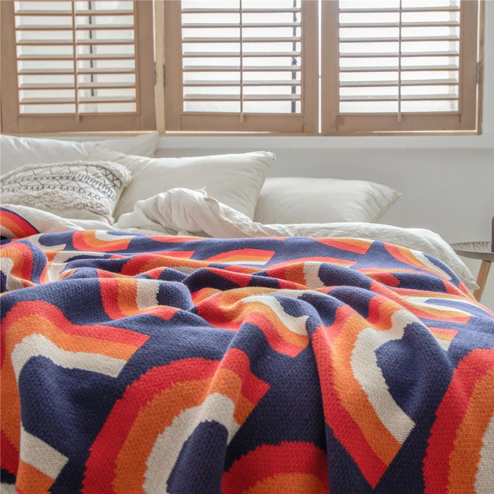 Blue red orange cream rainbow knitted blanket on bed