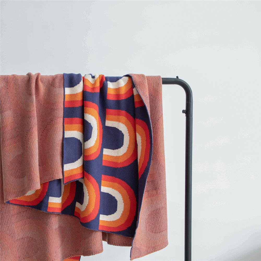 Blue red orange cream rainbow knitted blanket hanging over rail