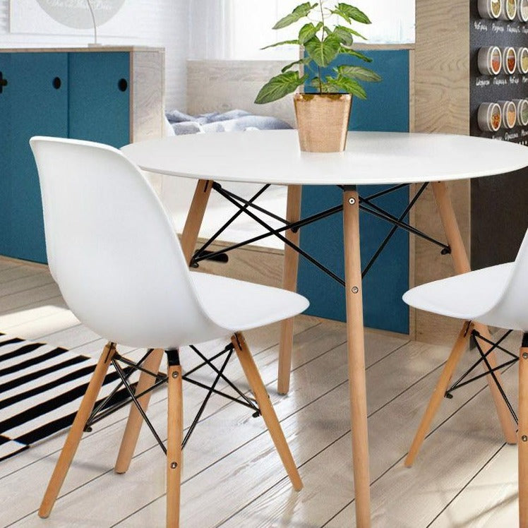 White 4 seater dining table with solid beech wood legs shown with chairs and household items