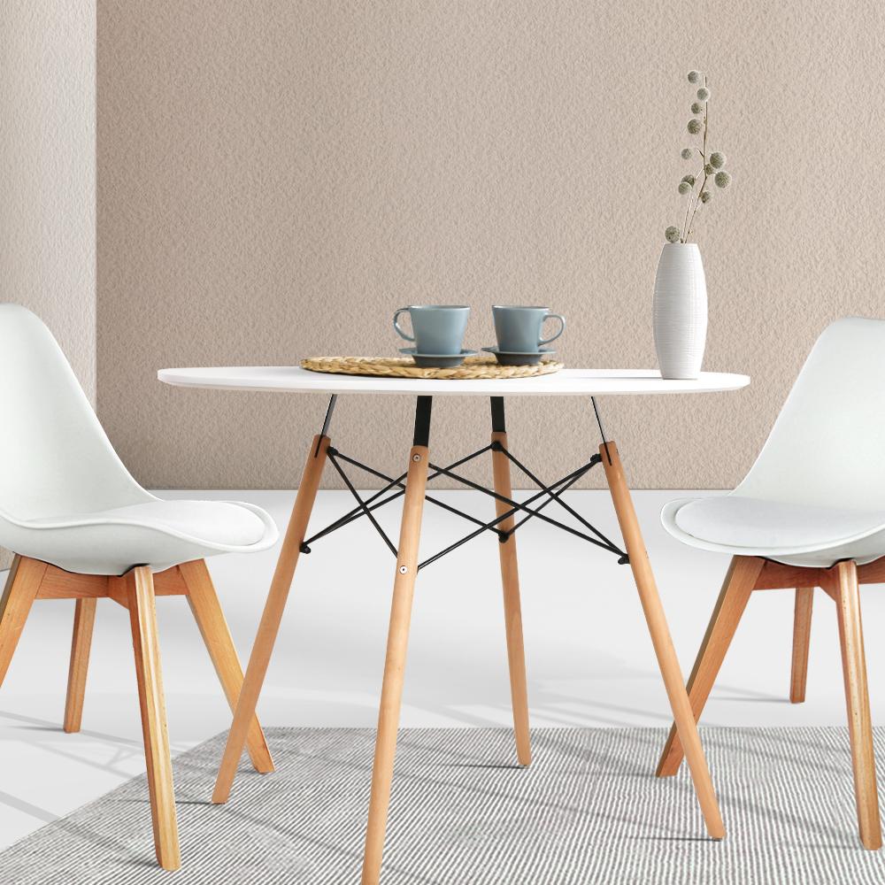 White 4 seater dining table with solid beech wood legs shown with dining chairs vase and tea cups