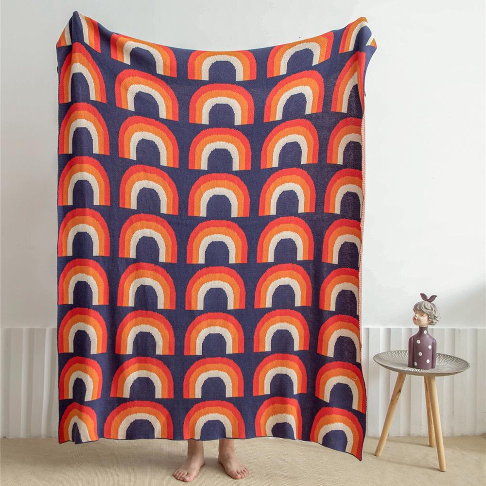 Blue red orange cream rainbow knitted blanket being held up