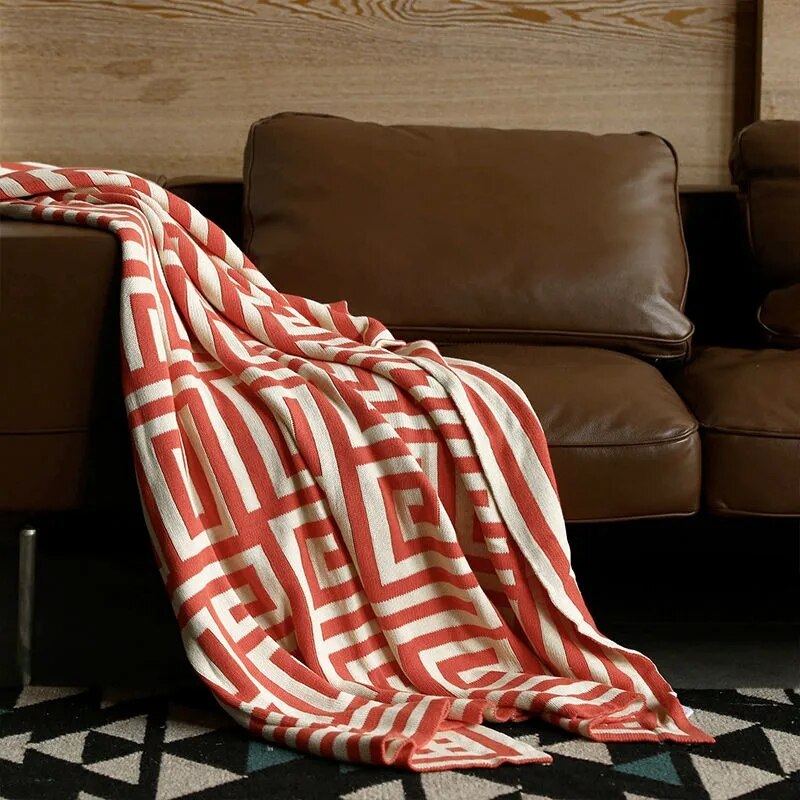 Red orange cream geometric throw rug on leather couch