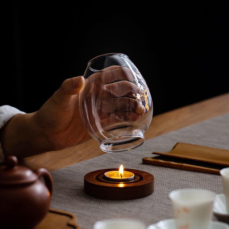 Glass candle holder with blossom branch and flowers on timber base