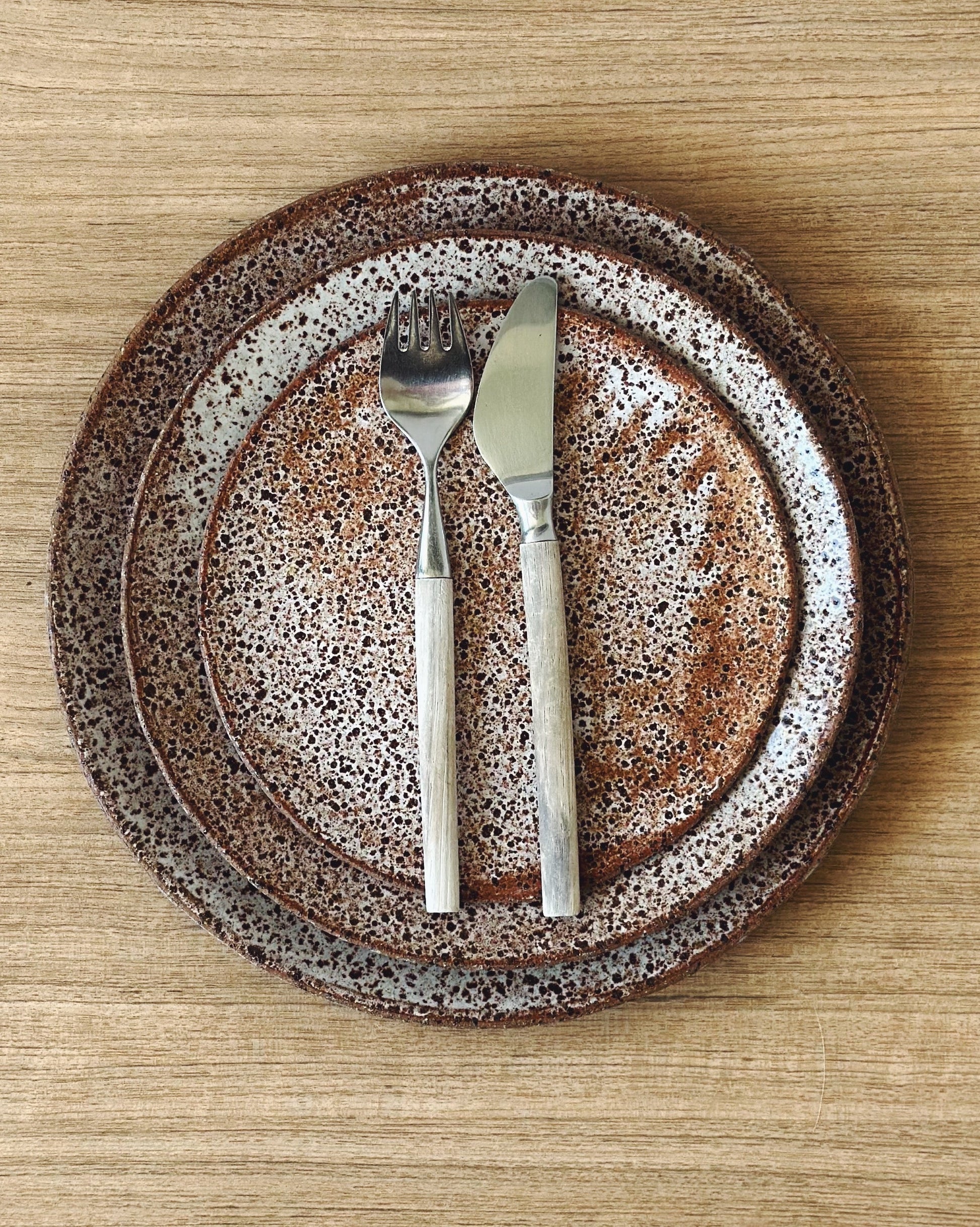 Speckled cream and brown handmade ceramic plates with knife and fork