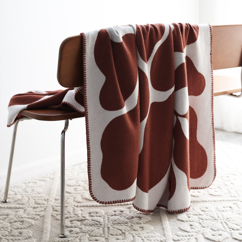 Rust red and white knitted blanket draped over chair