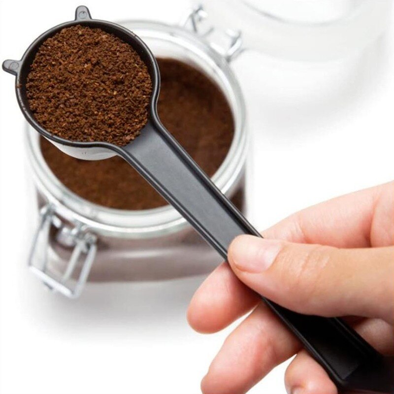 Person holding giraffe coffee scoop with coffee over jar of coffee