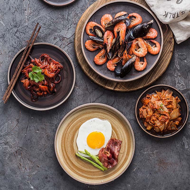 Charcoal and earth coloured plates in various sizes with food