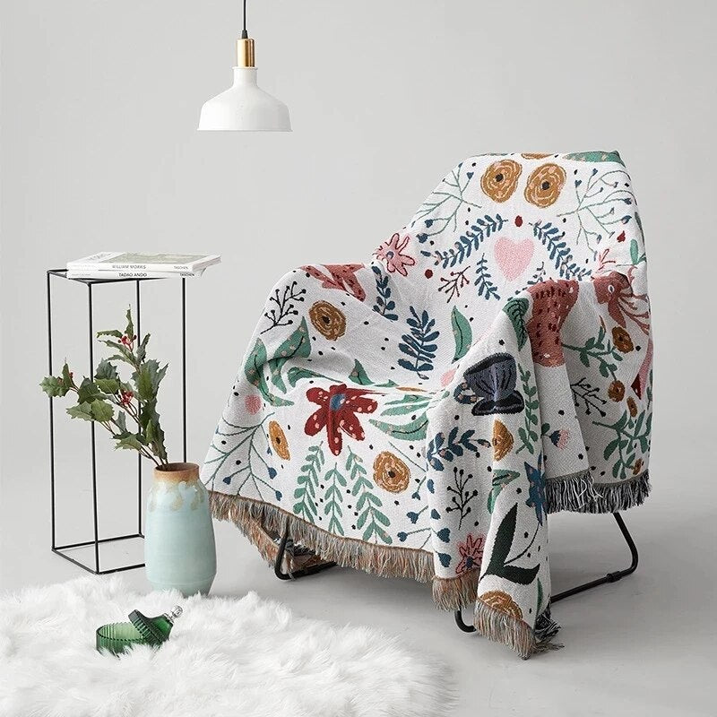 Whimsical nordic garden blanket featuring deer and flowers with fringed edge on chair