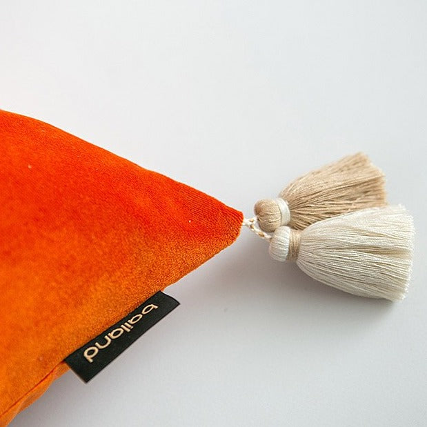 Close up of orange velvet cushion with tassel