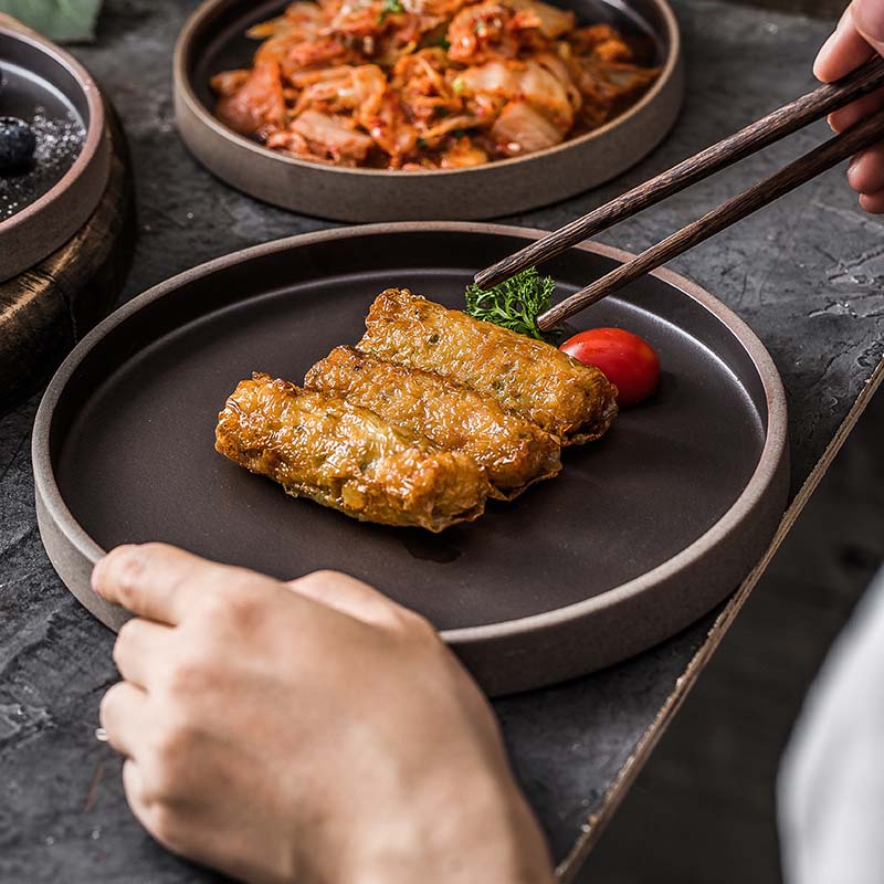 Charcoal plate with rim person eating food with chopsticks