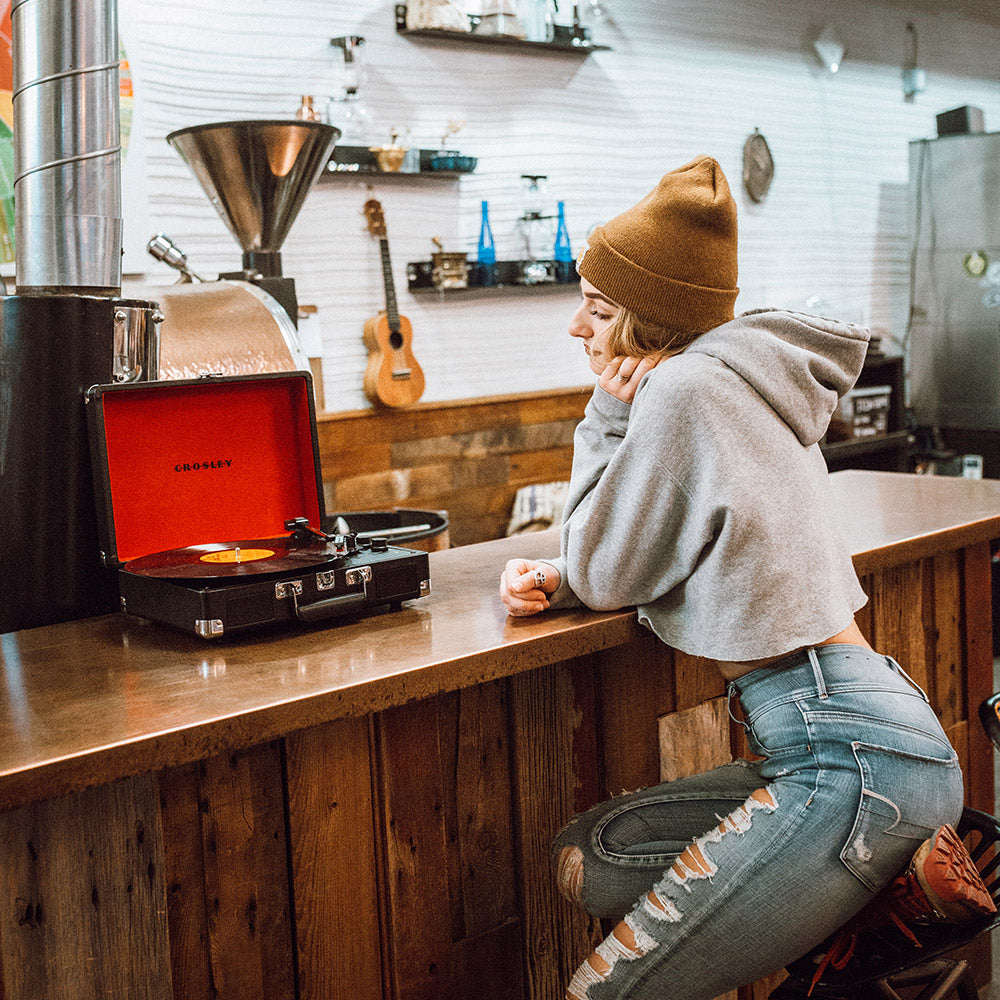 Woman listening to music with the Crosley Cruiser black Bluetooth portable turntable