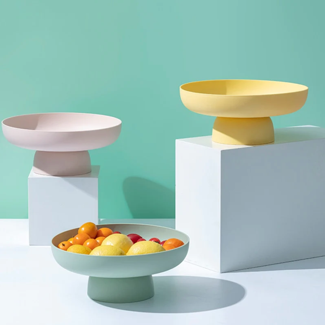 Pastel pink, green and yellow rounded elevated bowls with fruit