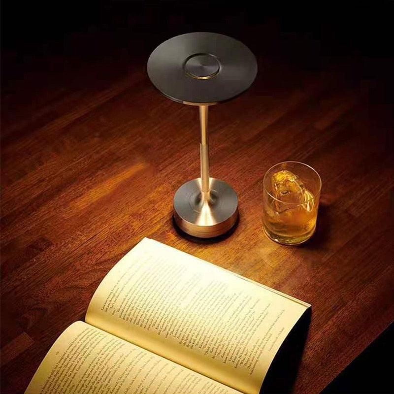 Disk top touch lamp from top view on table with drink and book