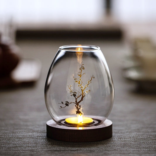 Glass candle holder with blossom branch and flowers on timber base