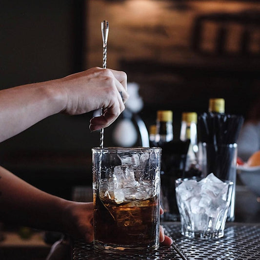 Silver cocktail spoon person mixing drink