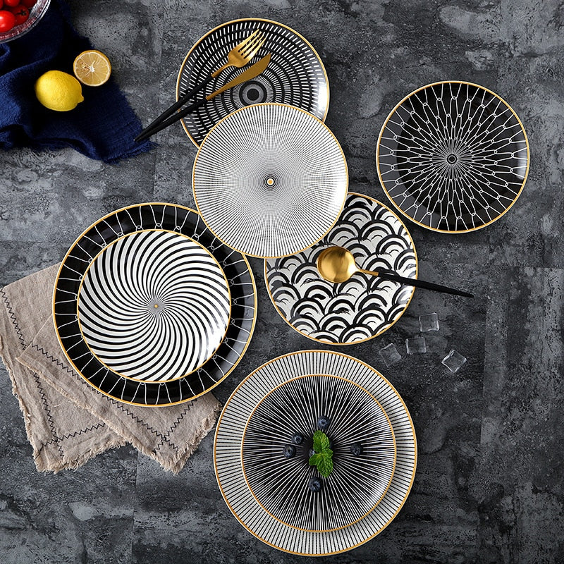 Black and white plates in various patterns with gold yellow edges