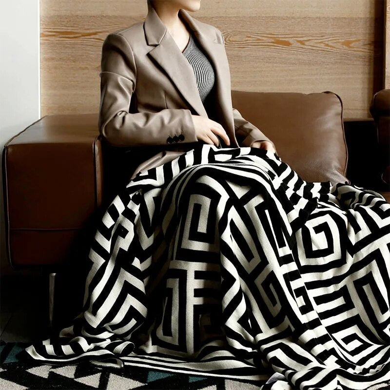 Women with black cream geometric knitted throw over knees