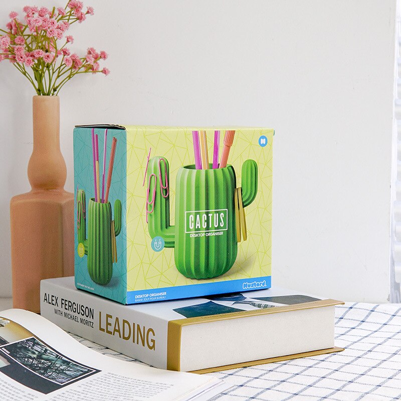 Boxed green cactus shaped desktop organiser sitting on book